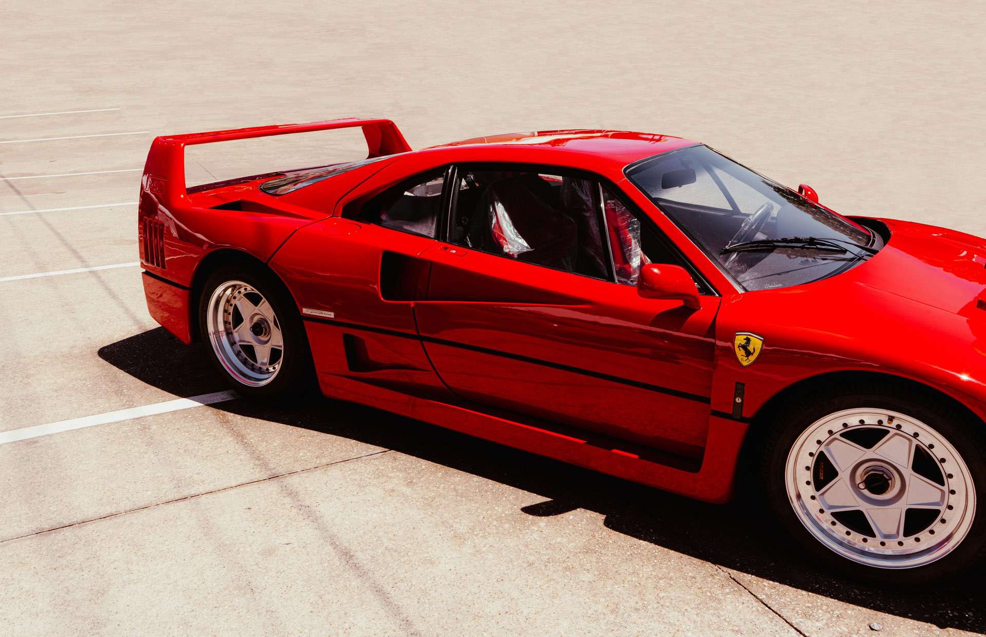 Ferrari F40 in an open parking lot with iconic badge on display.