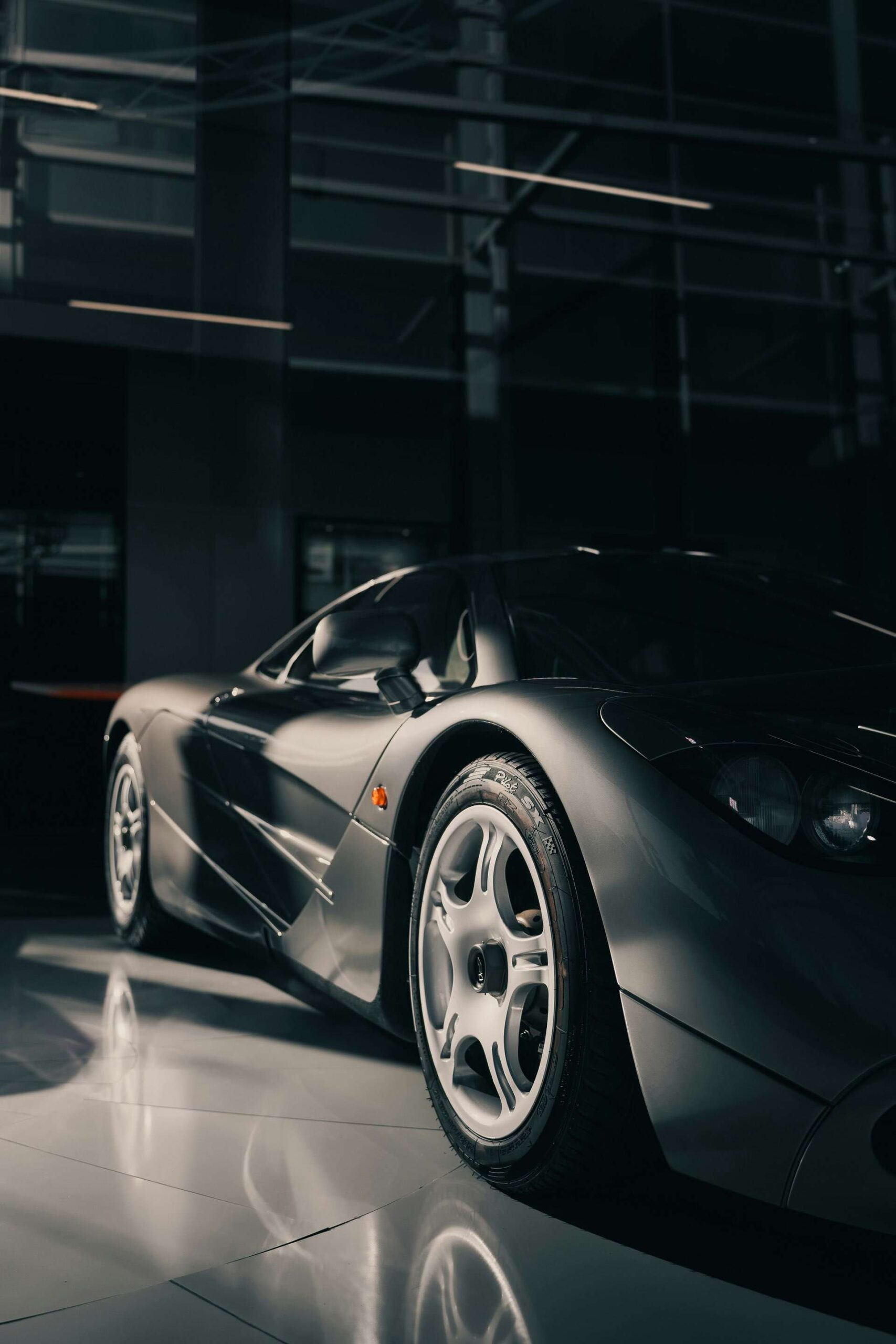 Dark lit super car in a garage highlighting the alloys and sleek aerodynamic design.