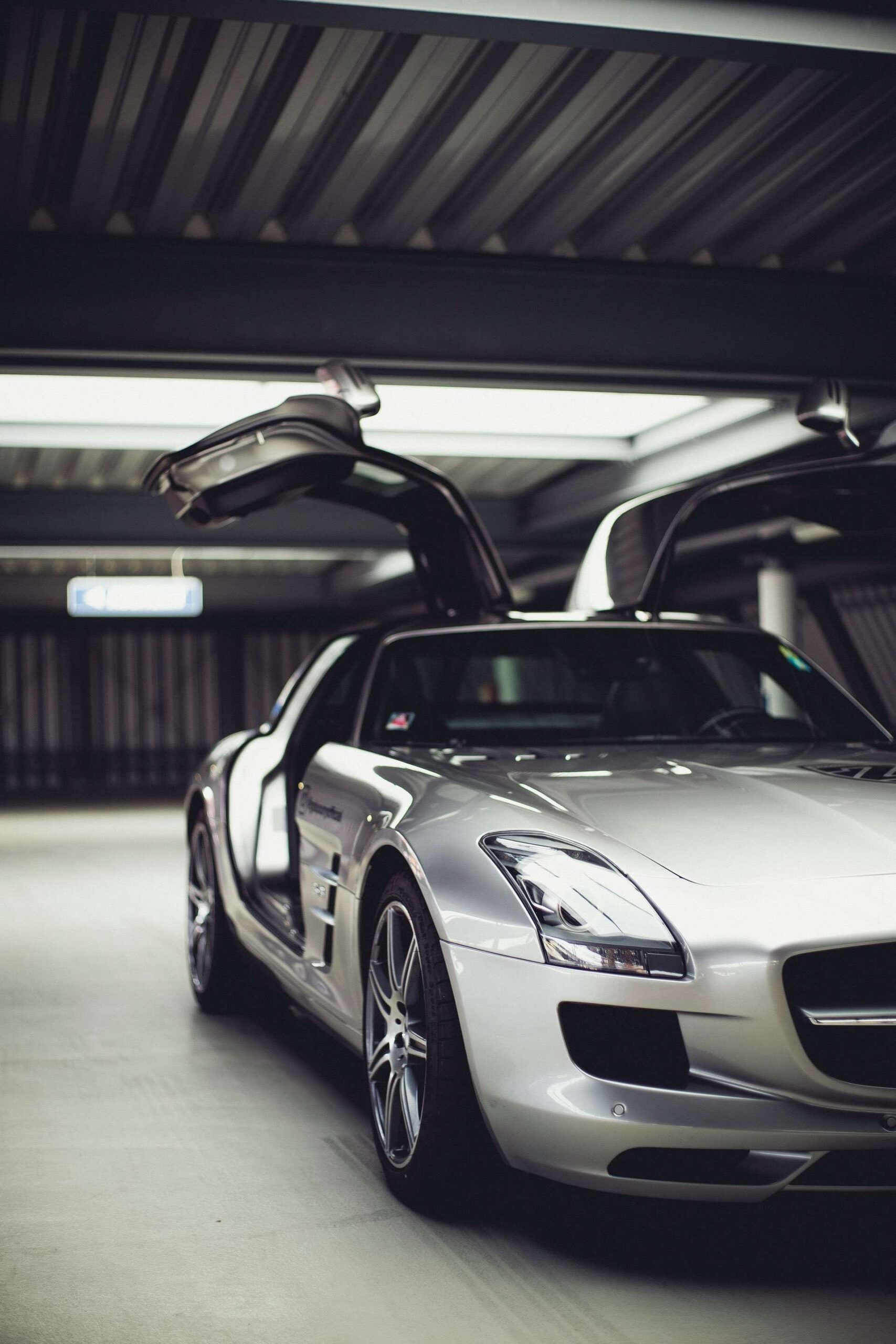 Classic mercedes with wing doors open parked in a dark light garage.