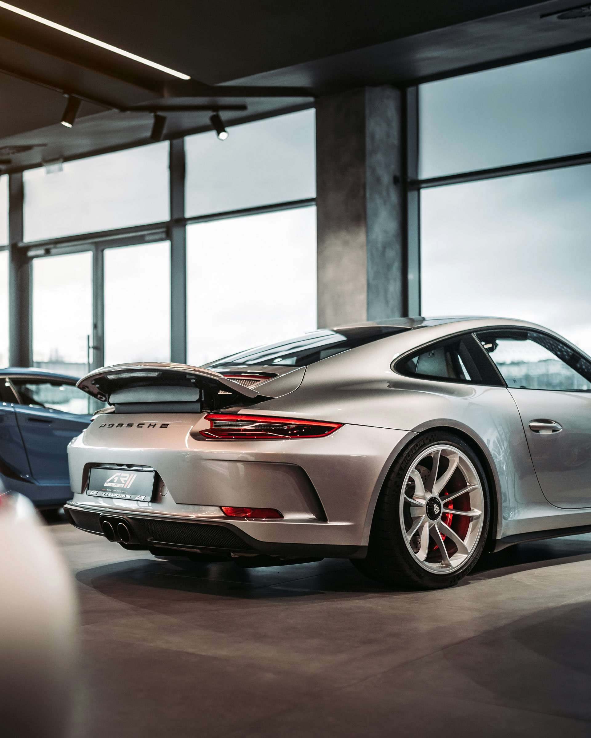 Rear end of a Porsche super car in a car showroom, highlighting the elegant iconic design.