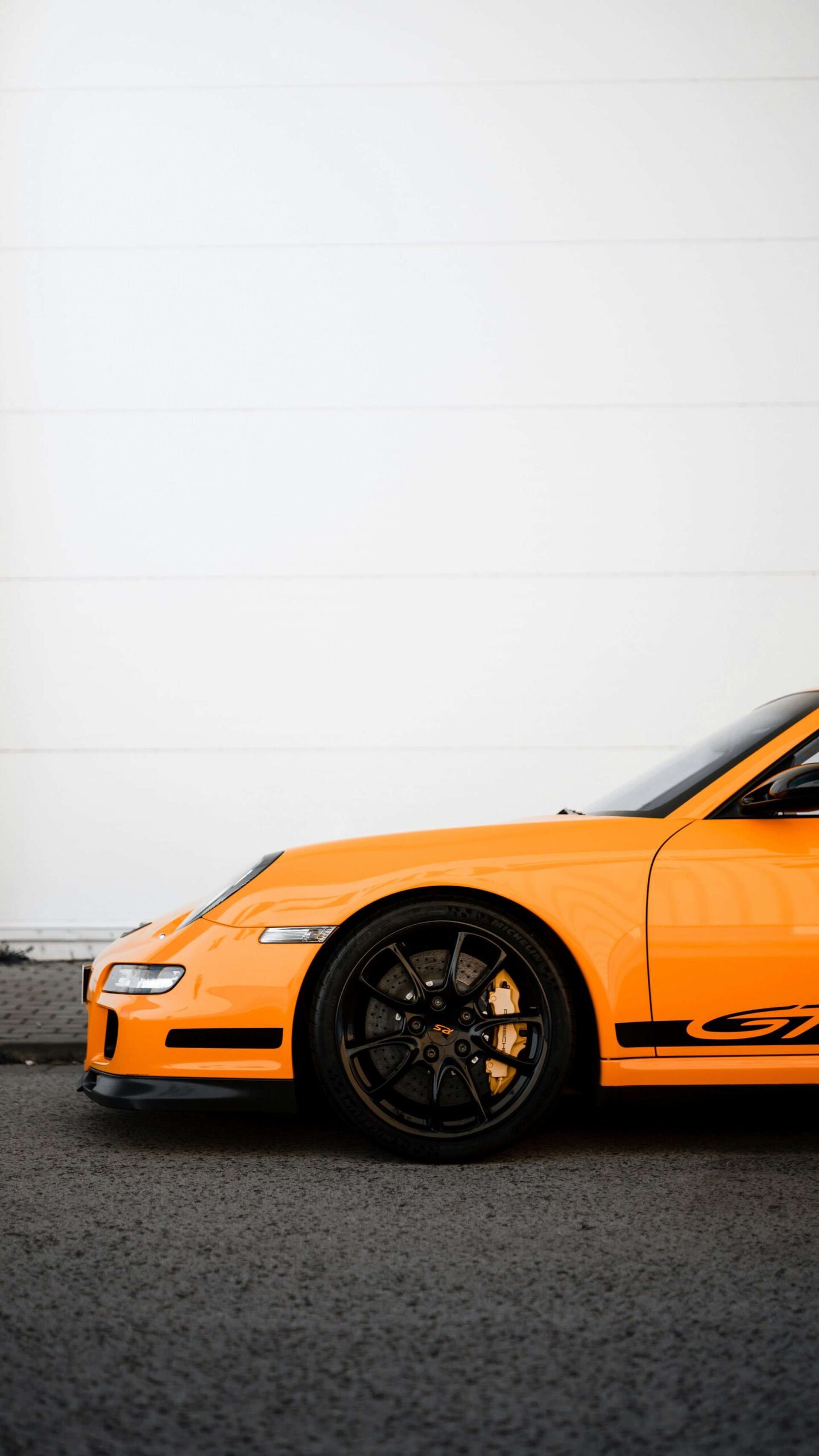 Porsche GT3 against a white wall, with the wheel and brake caliper as the centre of the shot.