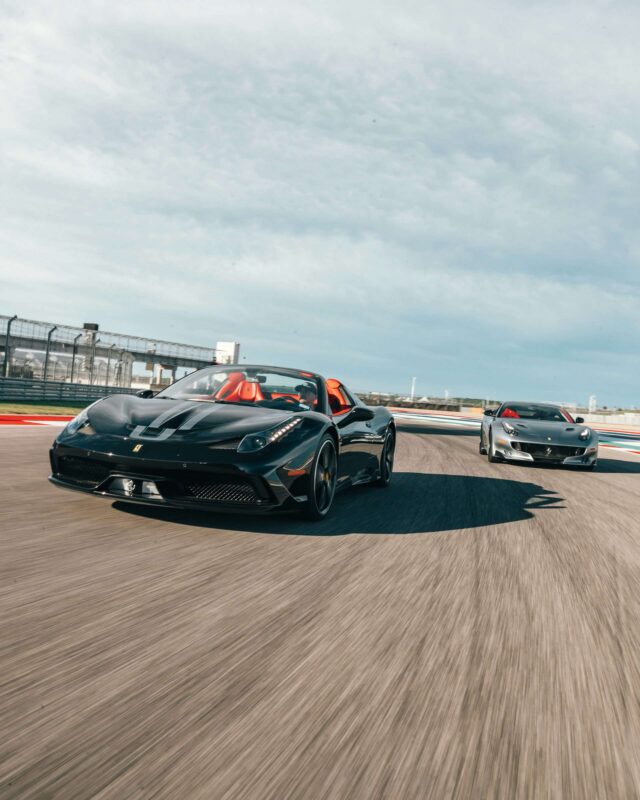 Two Ferrari super cars driving fast around a track side by side.