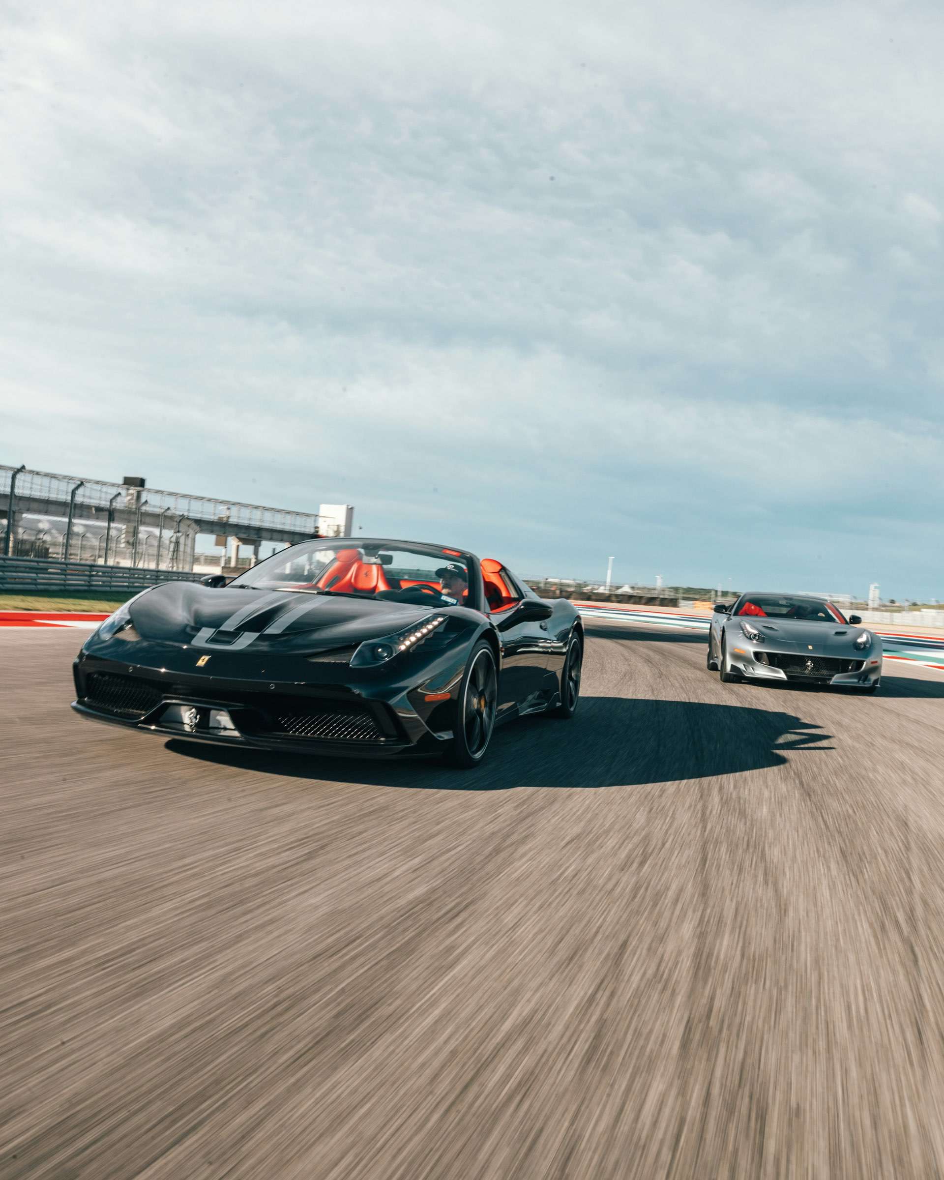 Two Ferrari super cars driving fast around a track side by side.