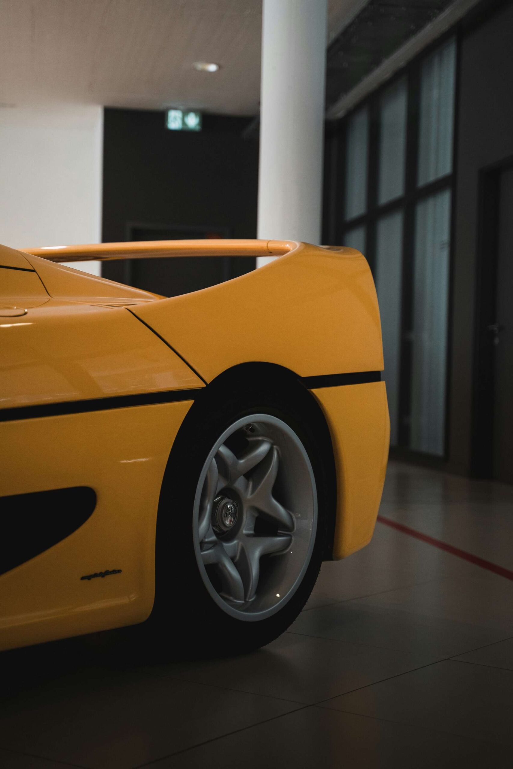 Rear end of a super car with a spoiler in a showroom.