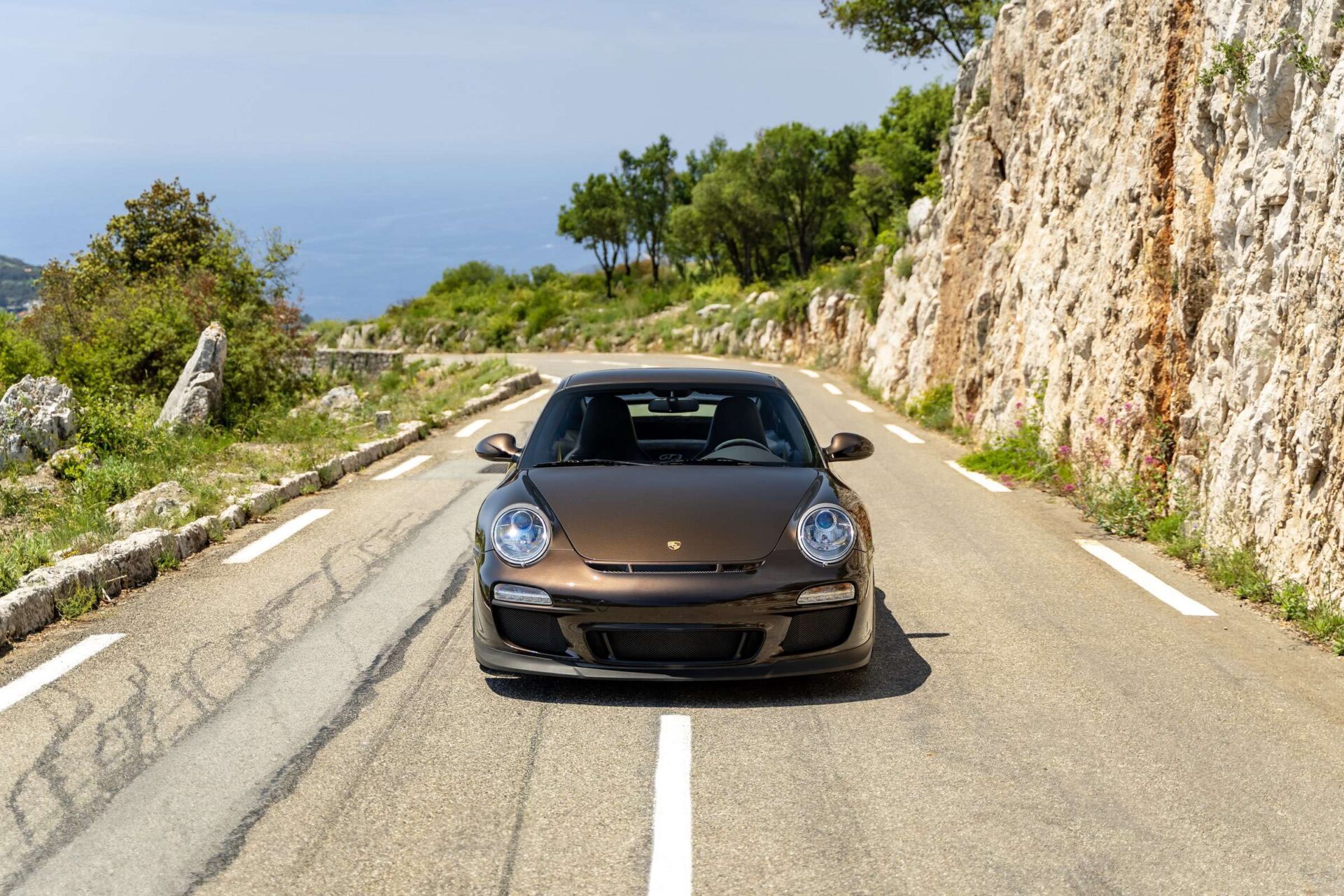 Front view shot of a Porsche driving along a mountain road.