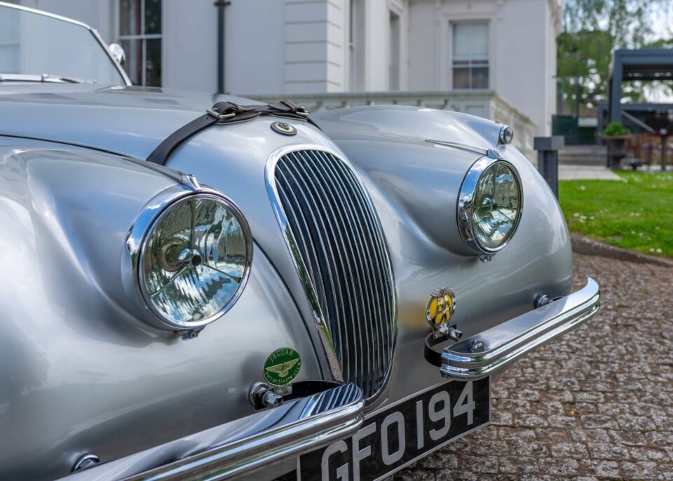 Close-up of the Jaguar XK120’s iconic badging and front grille.