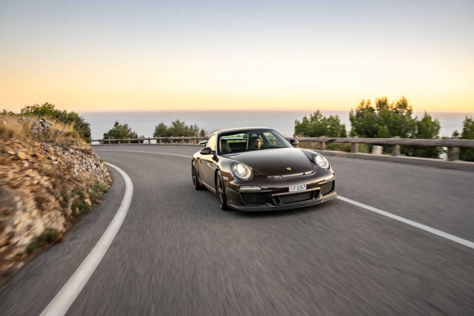 2010 Porsche 911 GT3 driving on an open road, showcasing its performance and sleek design.