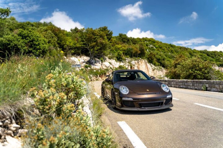 2010 Porsche 911 GT3 driving on an open road, showcasing its performance and sleek design.