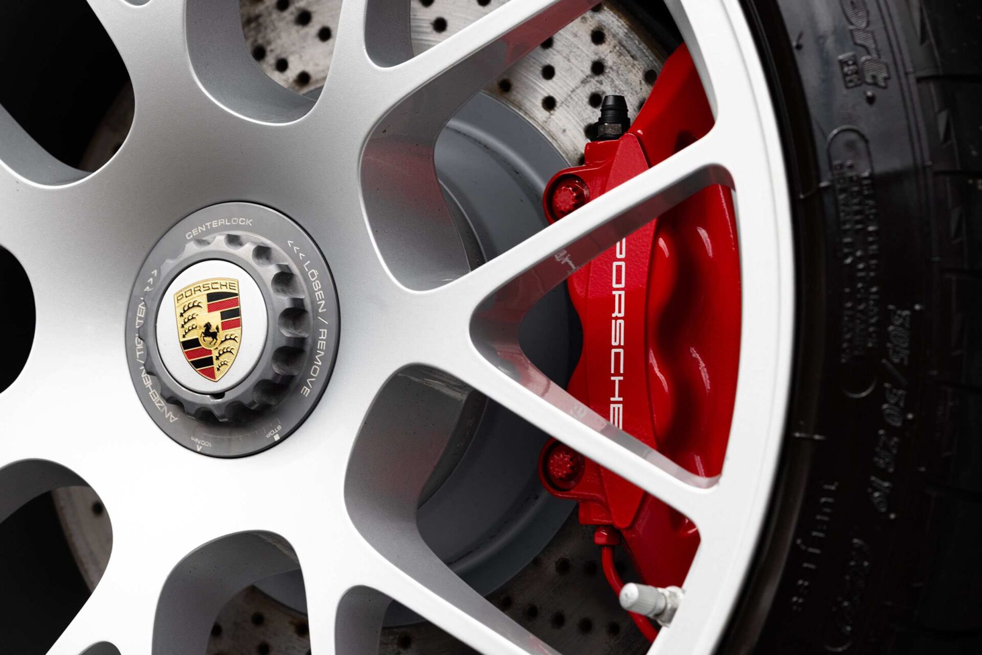 Close-up of the wheel and brake calipers on a high-performance Porsche supercar.